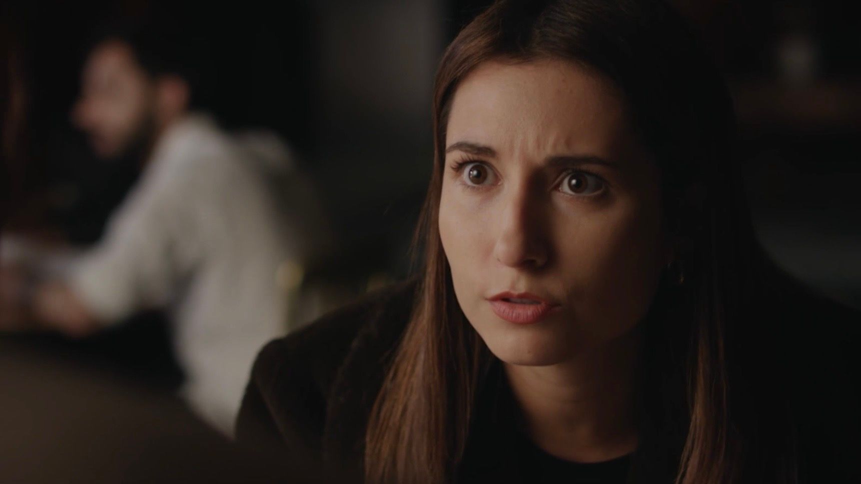 Jessica Curado in character during a conversation at a café table, with an intent expression.